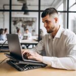 A man works at a laptop on his desk