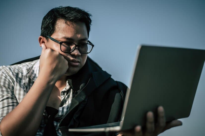 Man in Glasses is Solving Issues with a Laptop